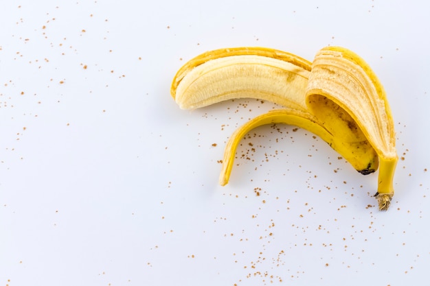 Une banane pelée dans la main d'une femme sur blanc