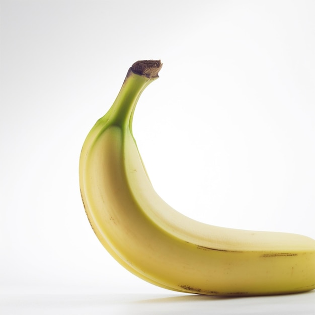Une banane avec une pointe verte est assise sur une surface blanche.