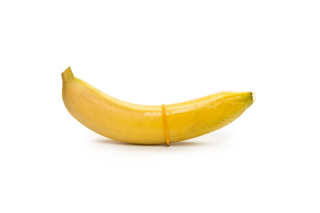 Une banane avec un préservatif dessus isolé sur fond blanc