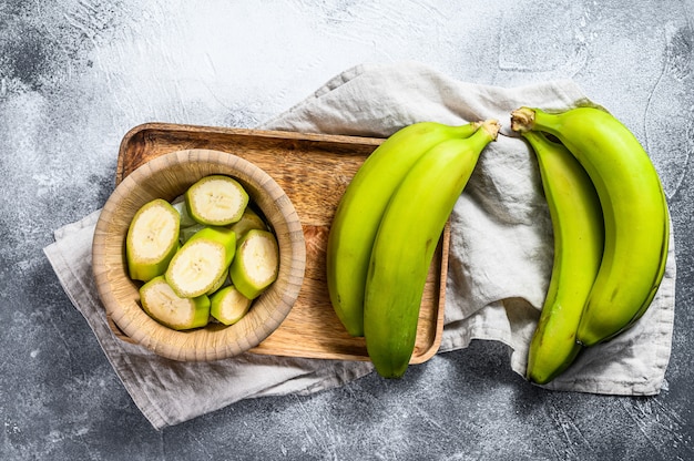 Banane verte tranchée dans un bol en bois.