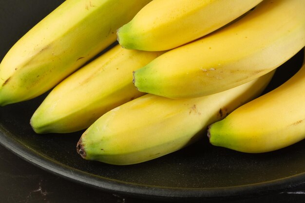 Des bananes sur une assiette noire en gros plan