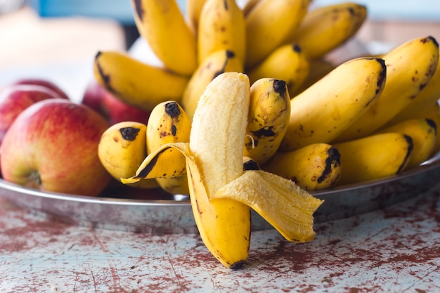 Bananes sur une assiette avec des pommes rouges.