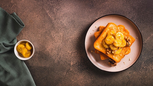 Bananes caramélisées avec des noix sur du pain frit sur une assiette de dessert sur le dessus de la table vue web bannière
