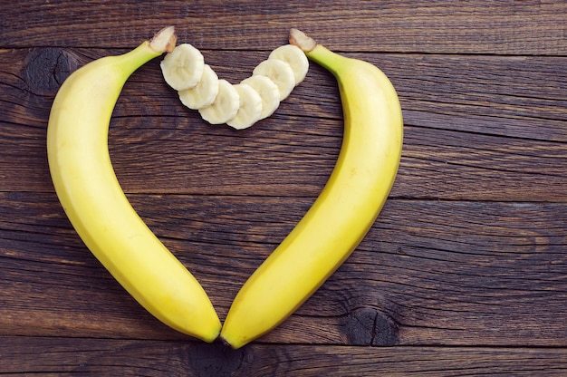 Photo bananes en forme de coeur sur table en bois foncé, vue de dessus