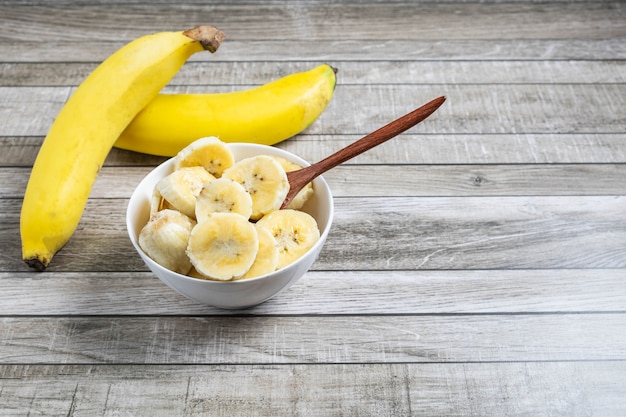 Bananes fraîches et bananes coupées en morceaux dans un bol pour la santé sur la table.