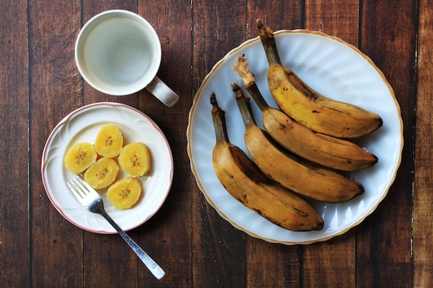 Bananes saba cuites à la vapeur et un verre d'eau pour le petit déjeuner Fond de table en bois marron