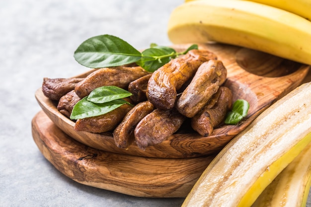 Bananes séchées au soleil dans un bol en bois sur fond de pierre