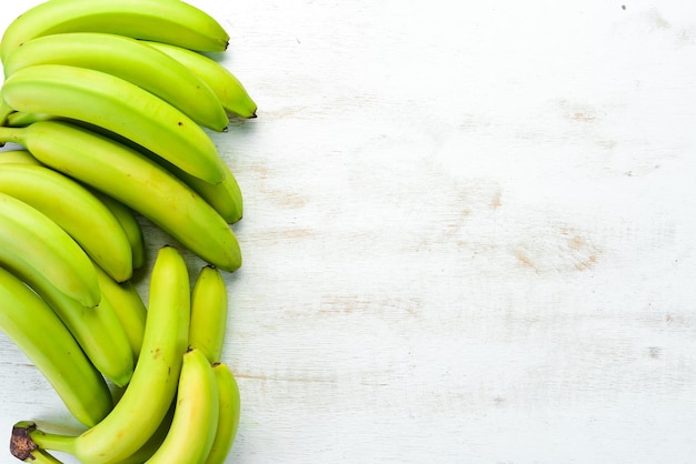 Photo bananes vertes fraîches sur fond de bois blanc vue de dessus espace libre pour votre texte