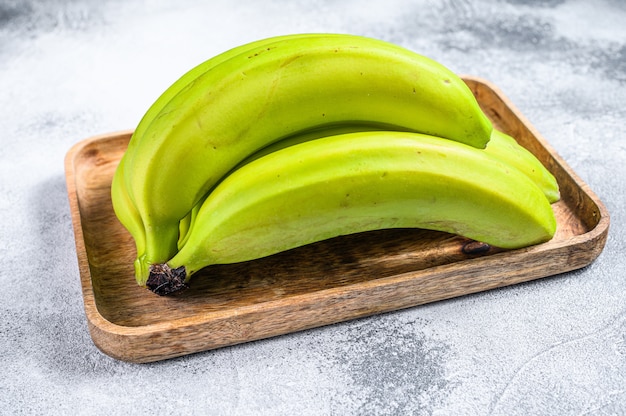 Bananes vertes sur un plateau en bois. Fond gris. Vue de dessus. Fruit exotique