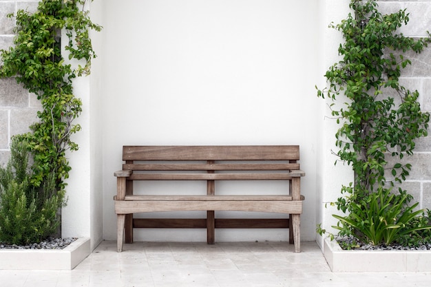 Banc en bois devant le mur de béton avec lierre