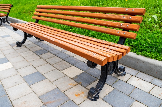 Banc en bois avec des jambes de fer dans un parc par une journée ensoleillée en été