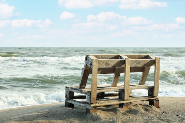 Photo banc en bois sur la plage de sable de la mer