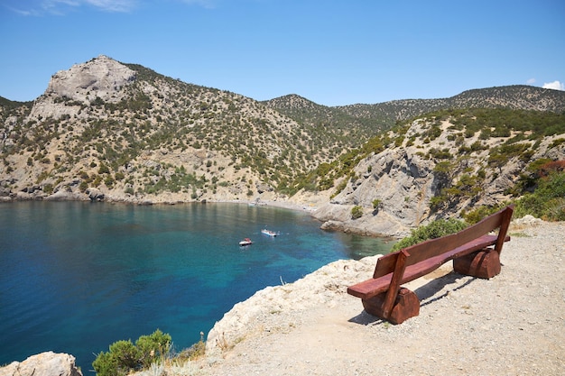 Photo banc en bois sur un rocher avec vue sur une magnifique baie aux eaux transparentes en été