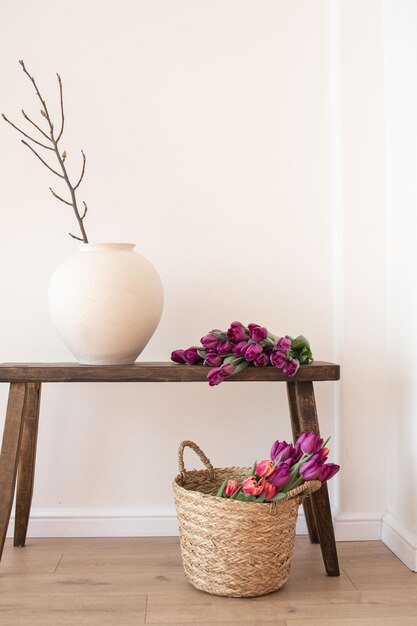 Banc de bois rustique avec un vase en céramique et un panier tissé avec des tulipes violettes