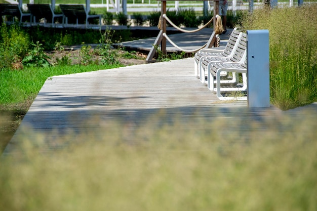 Un banc en bois se trouve sur une promenade avec une clôture et des arbres en arrière-plan