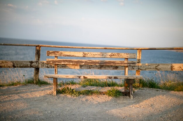 Banc en bois solitaire au bord de la mer au coucher du soleil