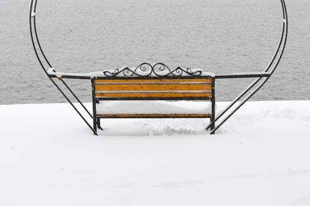 Banc en fer forgé enneigé vide sous forme de coeurs pour couple d'amoureux dans le parc d'hiver