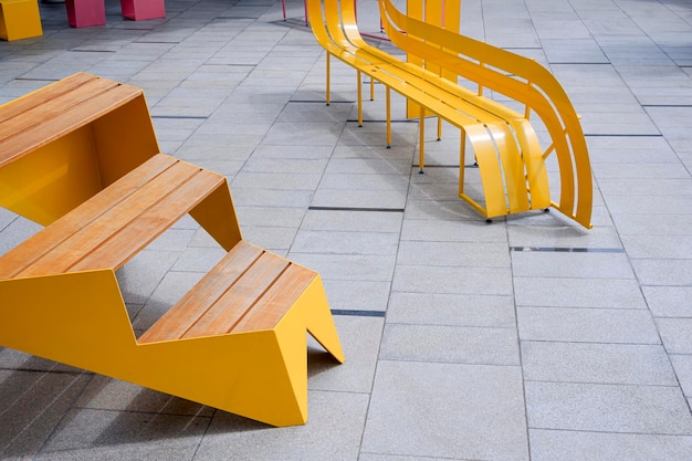 Photo banc moderne jaune vide sur un sol en carrelage de marbre gris dans une aire de repos publique