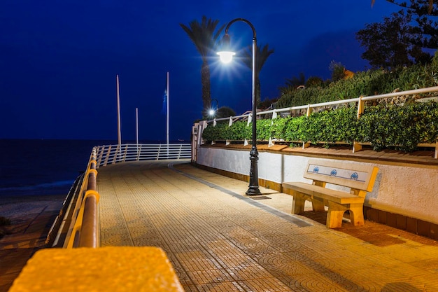 Banc placé le long de la passerelle près du littoral la nuit.