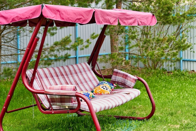 Banc rose swing avec un auvent sur un jardin gazonné vert