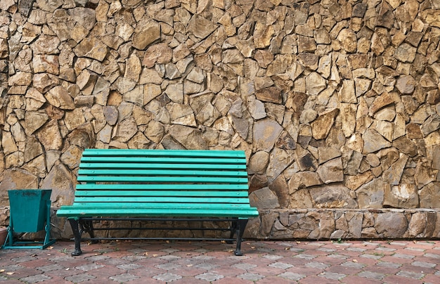 Banc vert se dresse contre un mur de pierre sauvage