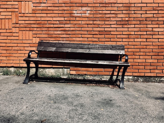 Photo un banc vide contre un mur de briques