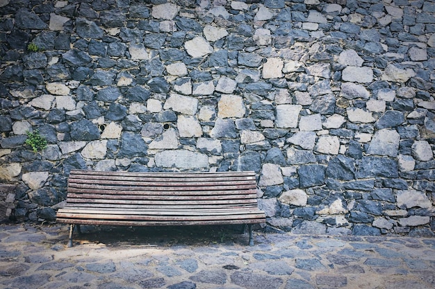 Un banc vide contre un mur de pierre