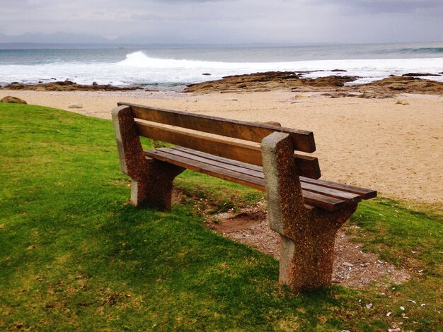 Un banc vide sur la plage par la mer contre le ciel