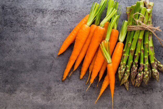 Banches d'asperges vertes fraîches et légumes sur fond de bois, vue du dessus