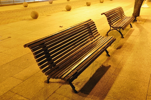 Bancs de ville pittoresques sous un éclairage nocturne jaune le long d'une passerelle piétonne