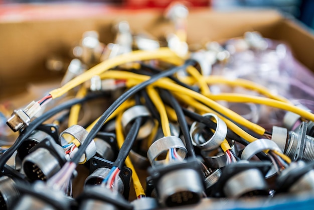 Bande de câbles colorés avec fiches pour connexion d'écrans TFT dans une caisse en carton dans l'atelier de l'usine de production vue rapprochée extrême