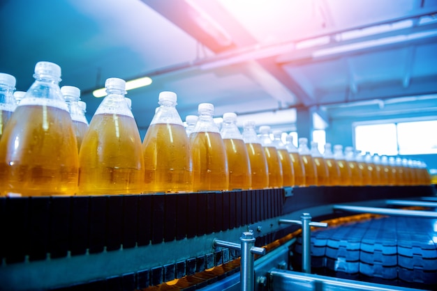 Bande transporteuse avec bouteilles de jus ou d'eau dans une usine de boissons moderne