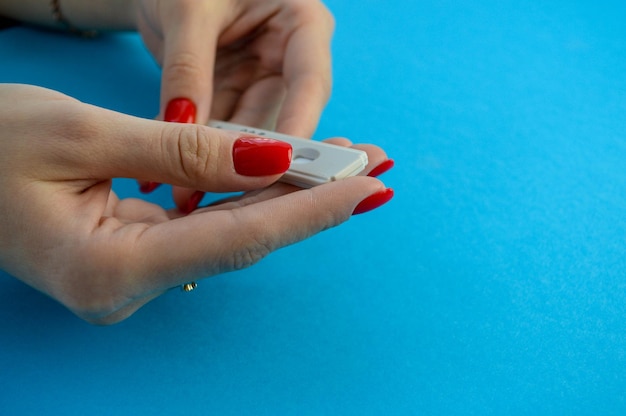 Bandelette de test de grossesse jetable fille avec manucure rouge fait un test pour déterminer la grossesse