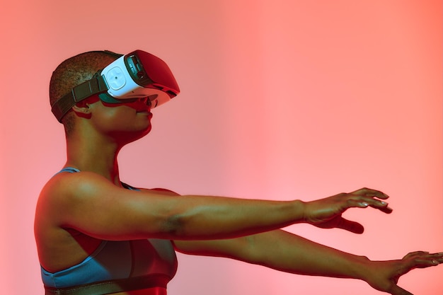 Banderole de femme afro-américaine jouant à un jeu vidéo à l'aide de lunettes de réalité virtuelle dans la salle de jeux