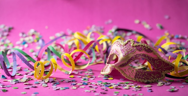 Banderoles de masque de carnaval et confettis sur fond rose
