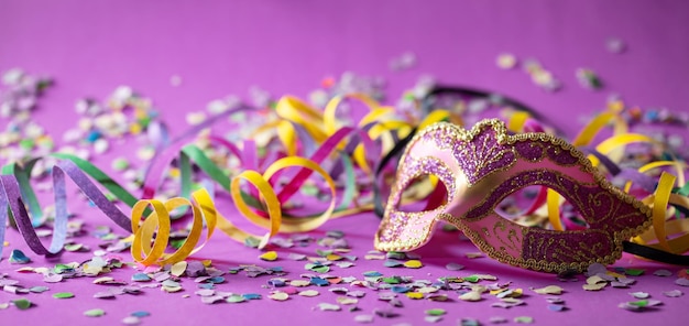 Banderoles de masque de carnaval et confettis sur fond violet