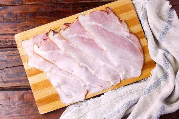 Bandes de bacon cru sur la planche à découper sur une table de cuisine en bois rustique. Nourriture américaine