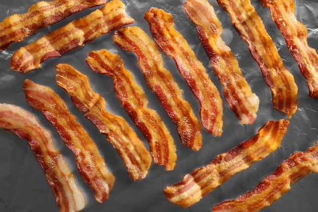 Des bandes de bacon frit en gros plan sur papier d'aluminium