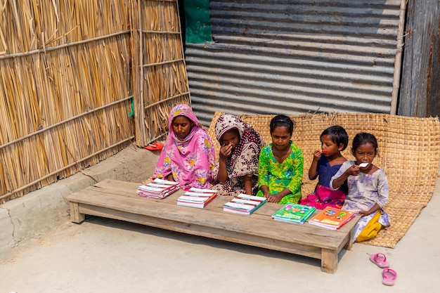 Bangladesh 06 mars 2021 Une enseignante est assise à l'extérieur devant une maison du village enseignant à certains des enfants pauvres de Majherchor Chandpur Chittagong