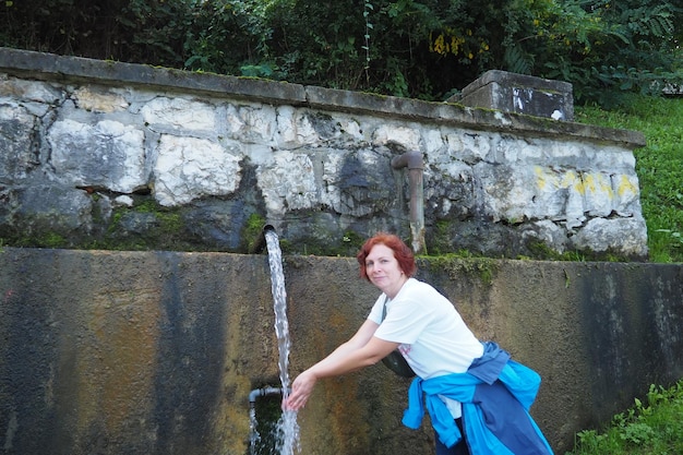 Banja Koviljaca Loznica Serbie Parc et forêt du mont Guchevo Source d'eau minérale sulfurique et ferrugineuse Ilidja Chesma Cesma Un jet d'eau se déverse d'un robinet dans un mur de béton Une femme