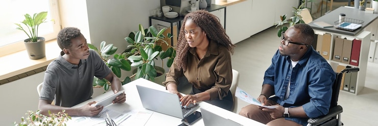 Photo banner du site web d'une jeune équipe afro-américaine de développeurs assise à une table blanche avec des ordinateurs portables et