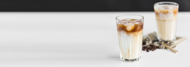 Bannière Café glacé dans un verre avec de la crème et des grains de café sur la table avec espace de copie