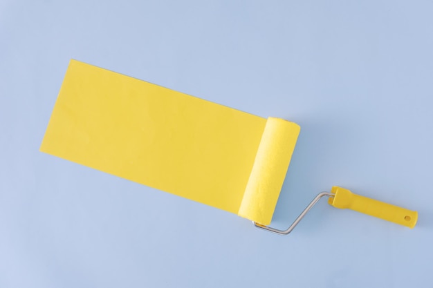 Photo bannière diagonale peinte en jaune avec effet rouleau à peinture et espace de copie sur fond bleu dans un panorama grand angle.