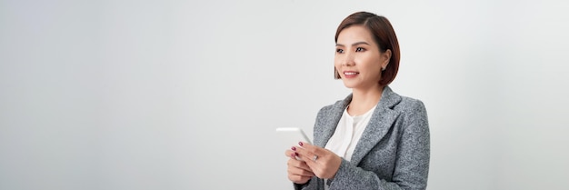 Photo bannière d'une femme d'affaires asiatique heureuse tenant un téléphone portable isolé sur un fond blanc