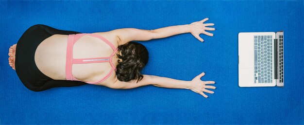 Bannière Femme asiatique pratiquant le yoga à la maison avec un ordinateur portable lors de l'épidémie de Covid19