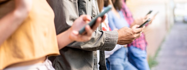 Bannière horizontale avec un groupe d'amis ennuyés à l'aide d'un smartphone assis dans la cour de l'université