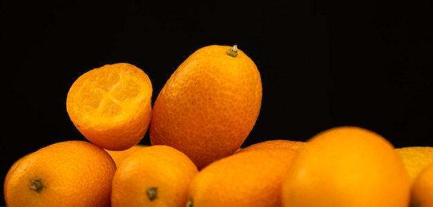 Bannière kumquat, agrumes frais sur fond noir. Cumquat, alimentation saine, concept de régime cru. Copier la photo de l'espace