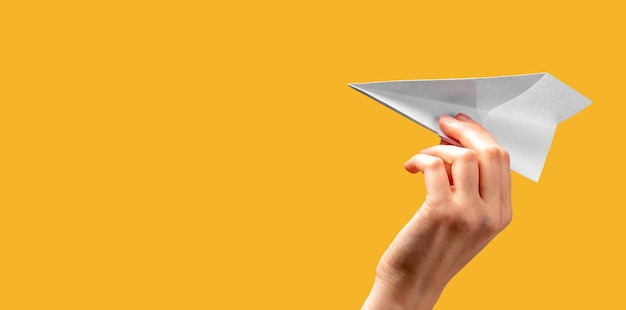 Photo bannière avec main de femme jetant un avion en origami sur fond orange concept de début de liberté art de pliage de papier place pour le texte