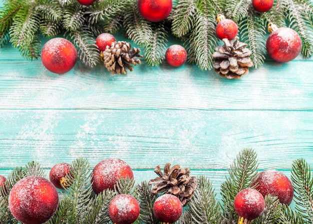 Bannière de Noël avec arbre vert, décorations de boule rouge, cônes sur fond en bois menthe sous la neige.