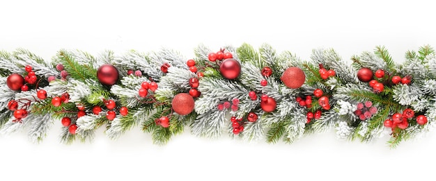 Bannière de Noël avec des boules rouges alignées sur des branches à feuilles persistantes enneigées